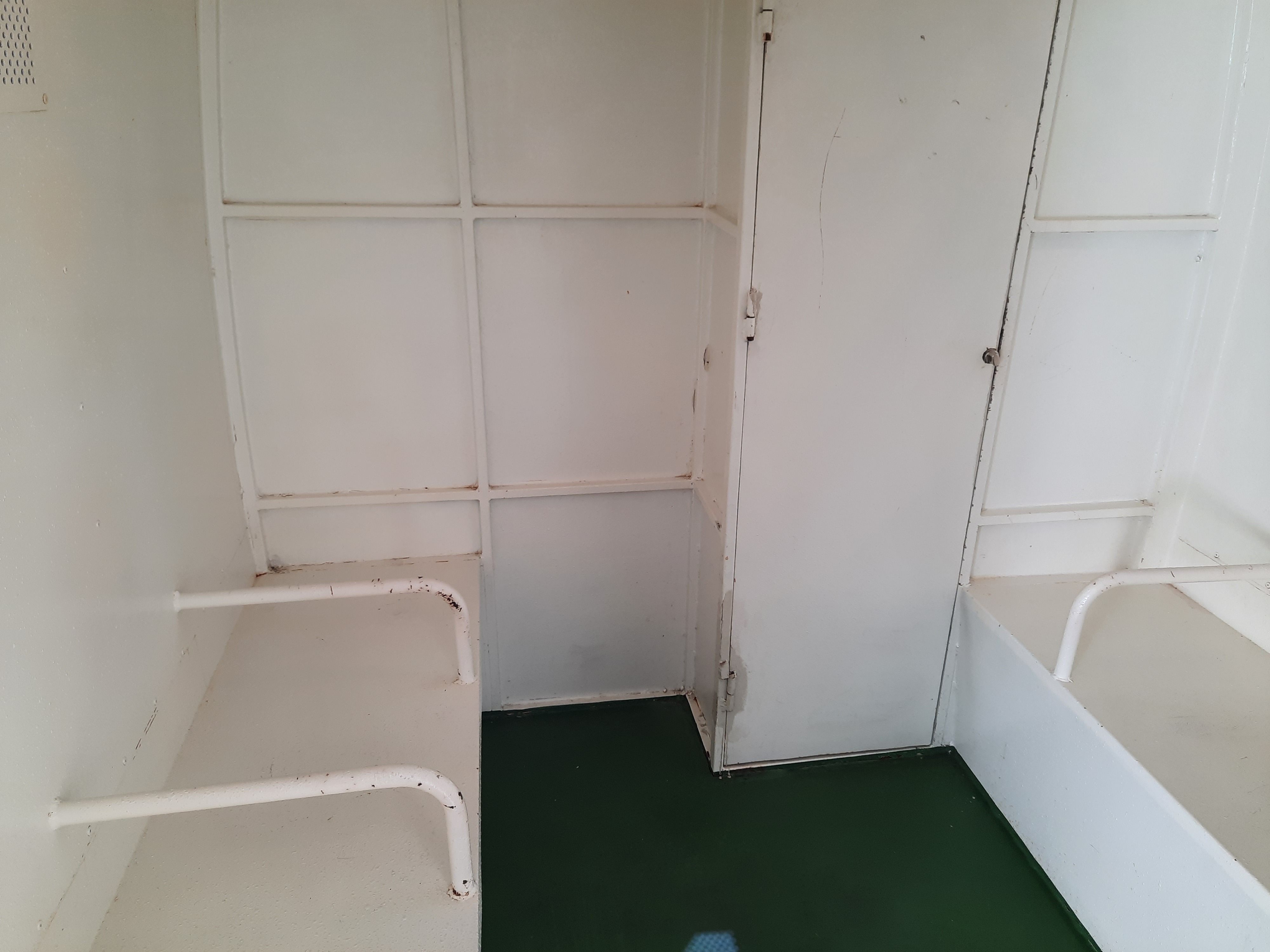 Asientos rudimentarios para presos y detenidos, sin cinturones de seguridad y orientados lateralmente.