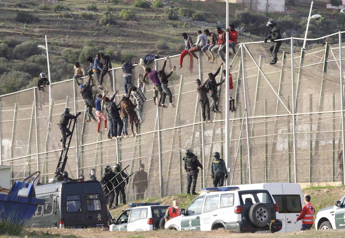 Inmigrantes y guardias civiles en la valla de Melilla