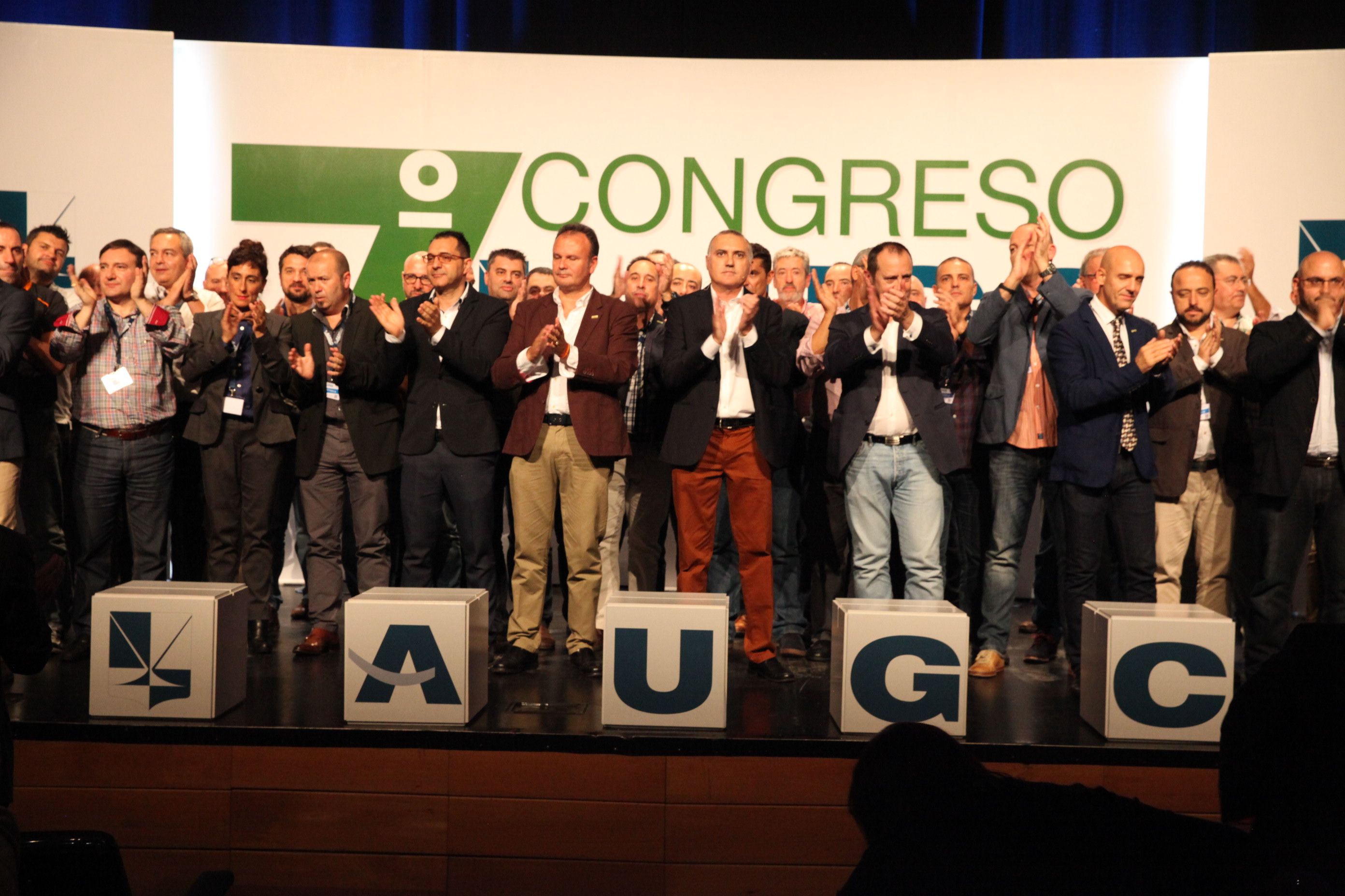 La Junta Directiva Nacional de AUGC y otros representantes de la organización saludan a los asistentes desde el escenario al finalizar el 7º Congreso Nacional