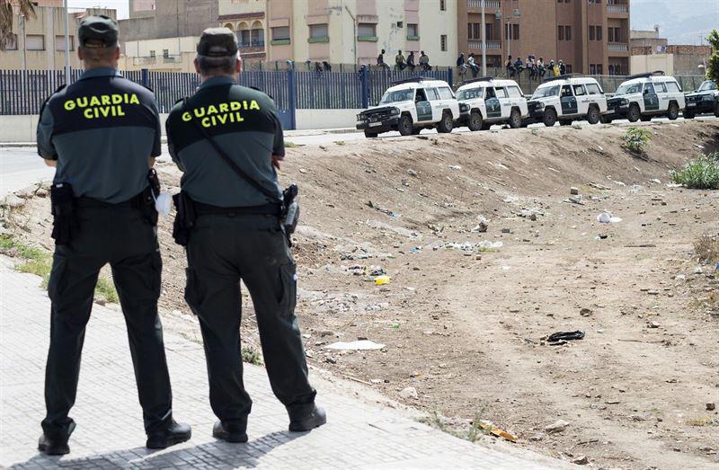 Dos guardias civiles vigilan una valla fronteriza.
