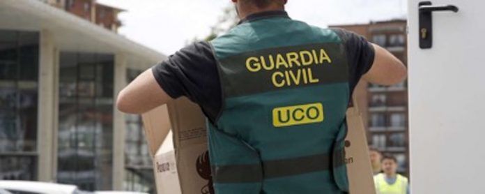 Un agente de la UCO carga una caja con documentación realacionada con una investigación.