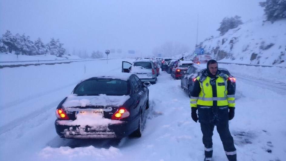 Un guardia civil junto a vehículos atrapados por el temporal en la AP6.