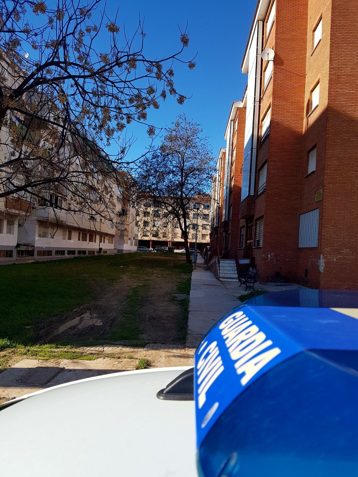 Un vehículo oficial presta vigilancia al bloque de viviendas de la Guardia Civil que había sido 'okupado' en una barriada de Badajoz.