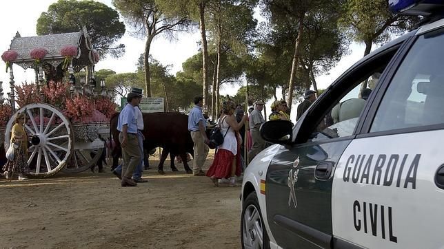 Un vehículo de la Guardia Civil ante participantes en la romería de El Rocío.