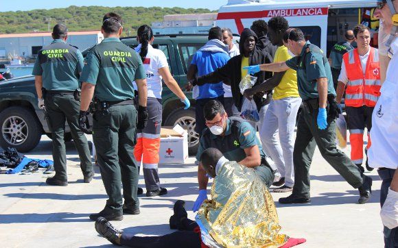 Guardias civiles atienden a inmigrantes recién llegados a la costa.