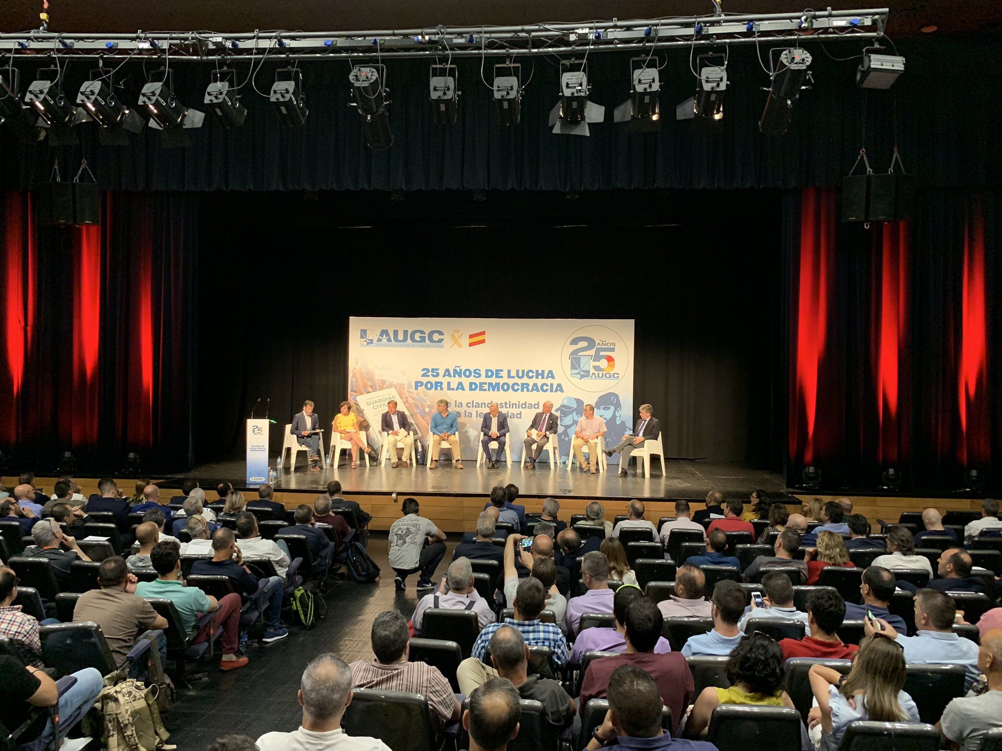 Vista panorámica del salón de actos en el que se celebró el evento. Al fondo, el escenario y los participantes en el debate.