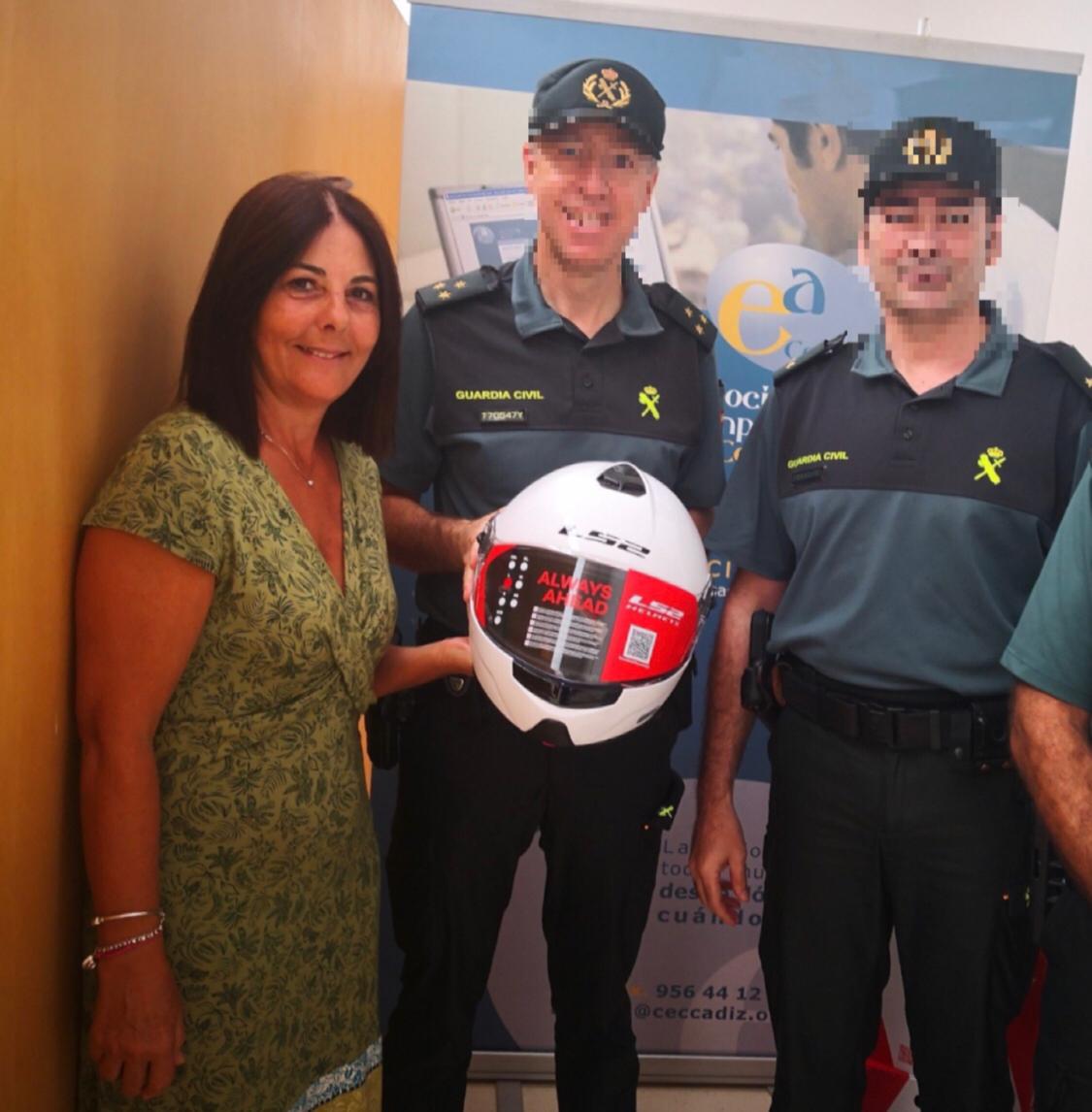 Una representante de la Asociación de Empresarios de Conil hace entrega de uno de los cascos a unos agentes.