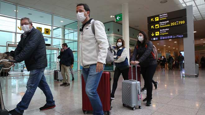 Viajeros se protegen con mascarillas del coronavirus