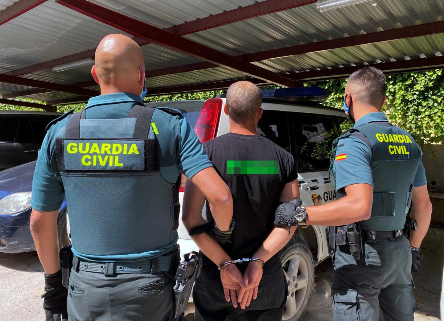 Guardias civiles equipados con chalecos antibalas conducen a un detenido.