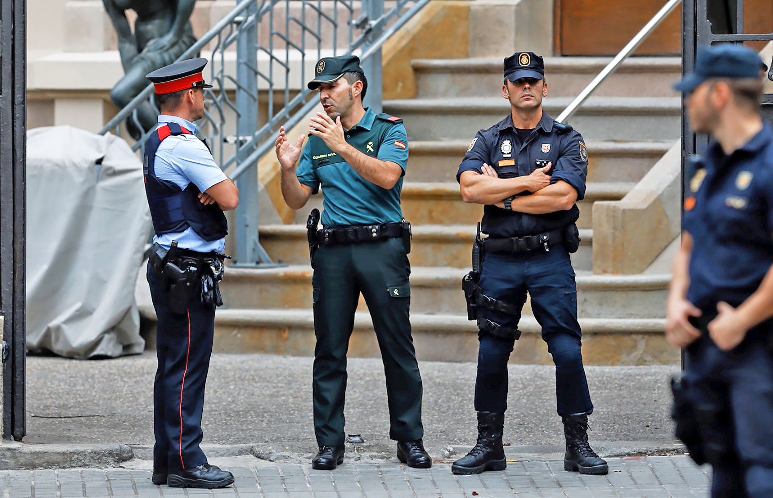 Un mosso conversa con un guardia civil en presencia de dos policías nacionales.